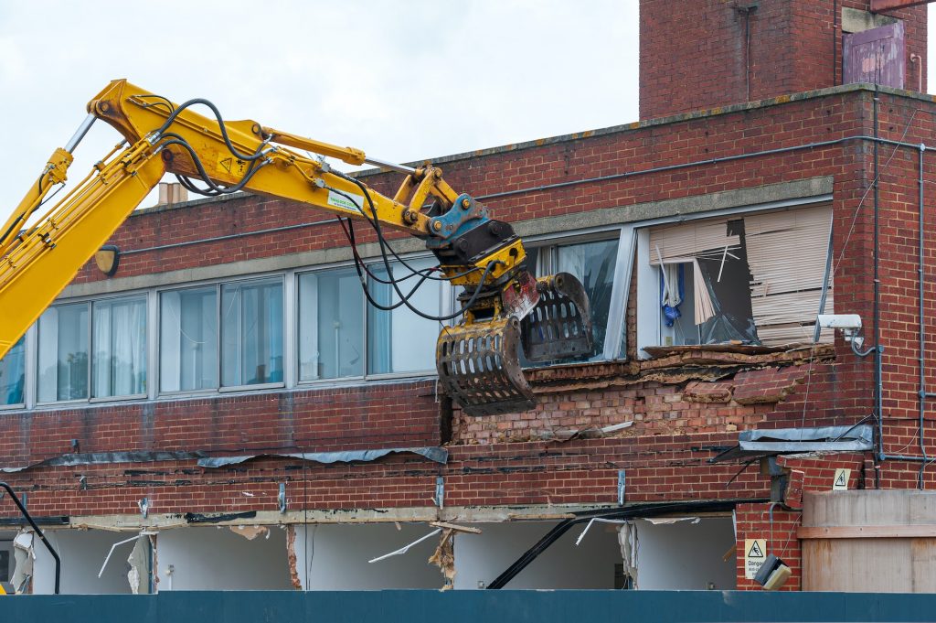 Demolition of an old building with a long reach machine hydraulic jaw.